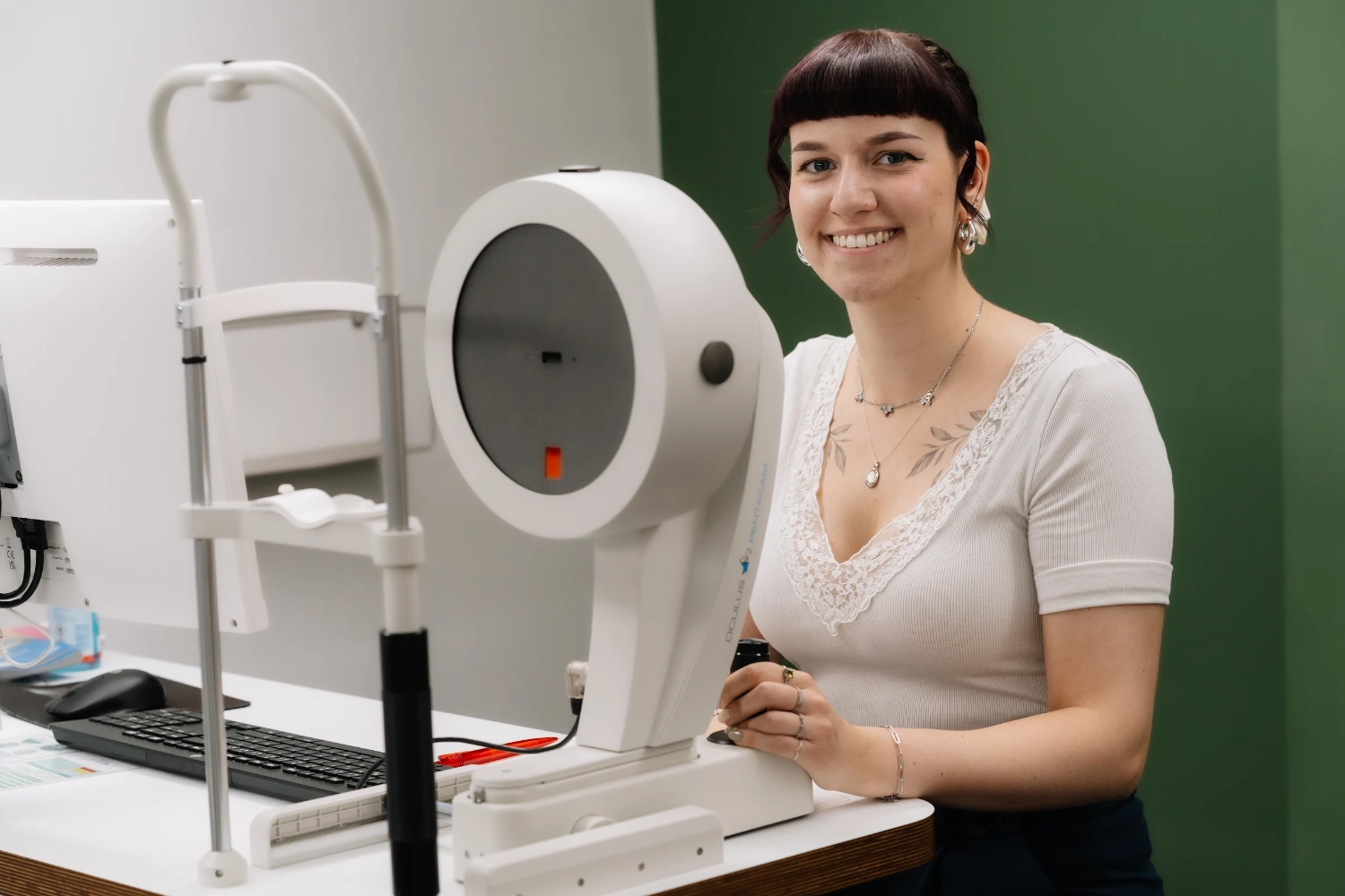 Eine dunkelhaarige Frau mit weißem T-Shirt sitzt vor einem Optiker-Messgerät.
